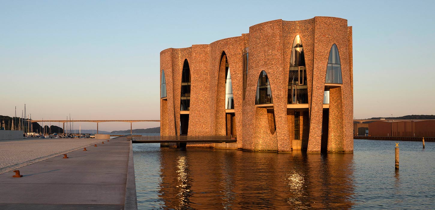 Fjordenhus mit Sonne darauf bei Sonnenuntergang