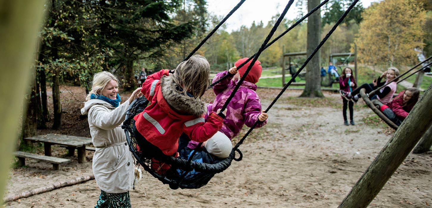Children on swings at the forest playground in Sønderskoven in Vejle