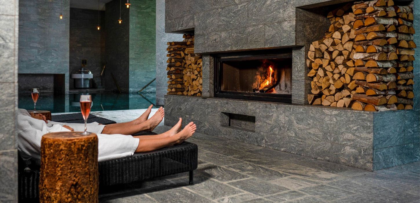 Couple in front of the fireplace with wine at Hotel Vejlefjord