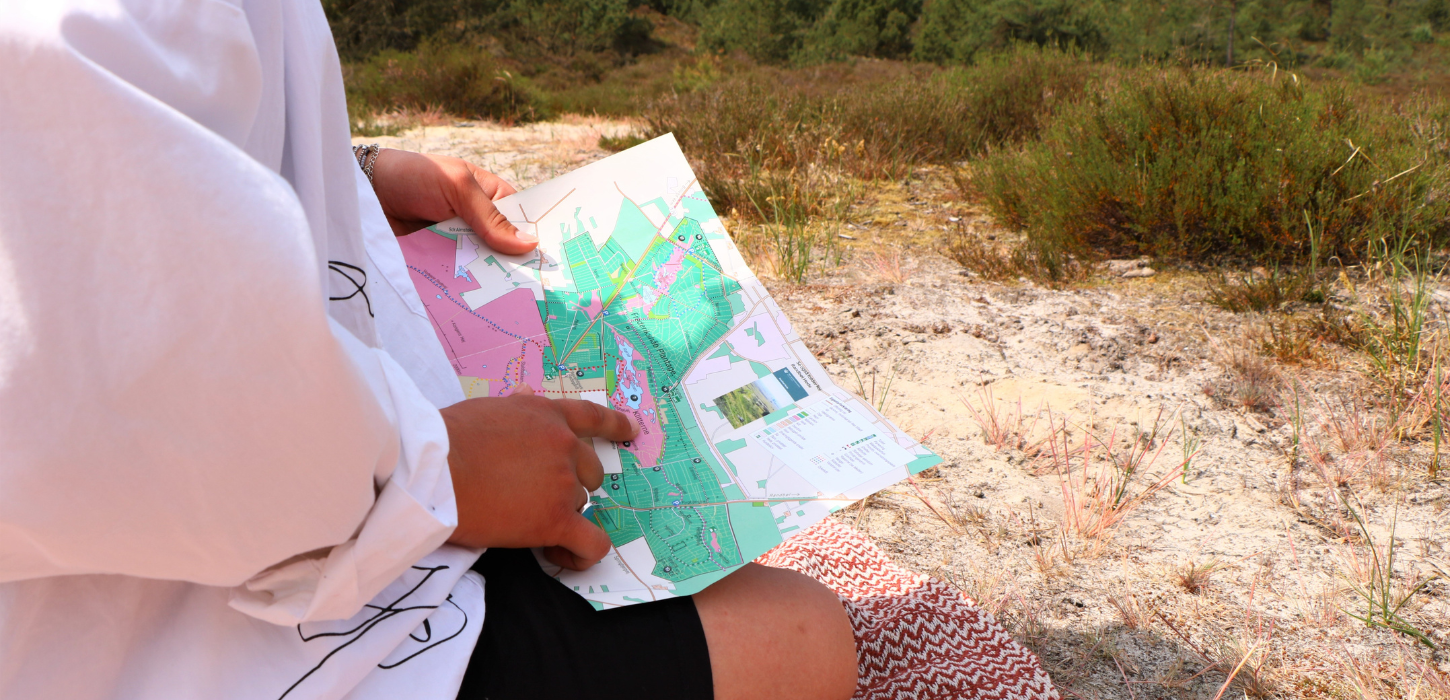 Touristen sitzen mit Wanderbroschüre in der Frederikshåb Plantage
