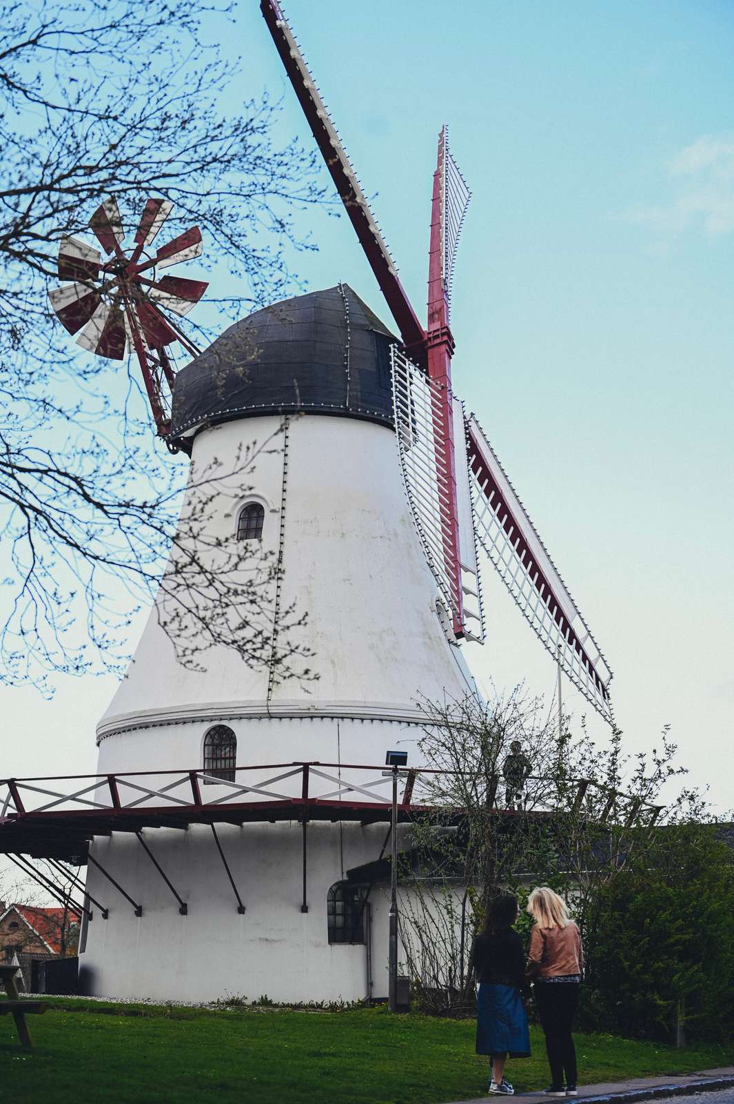 To personer står og kigger op på Vejle Vindmølle en forårsdag
