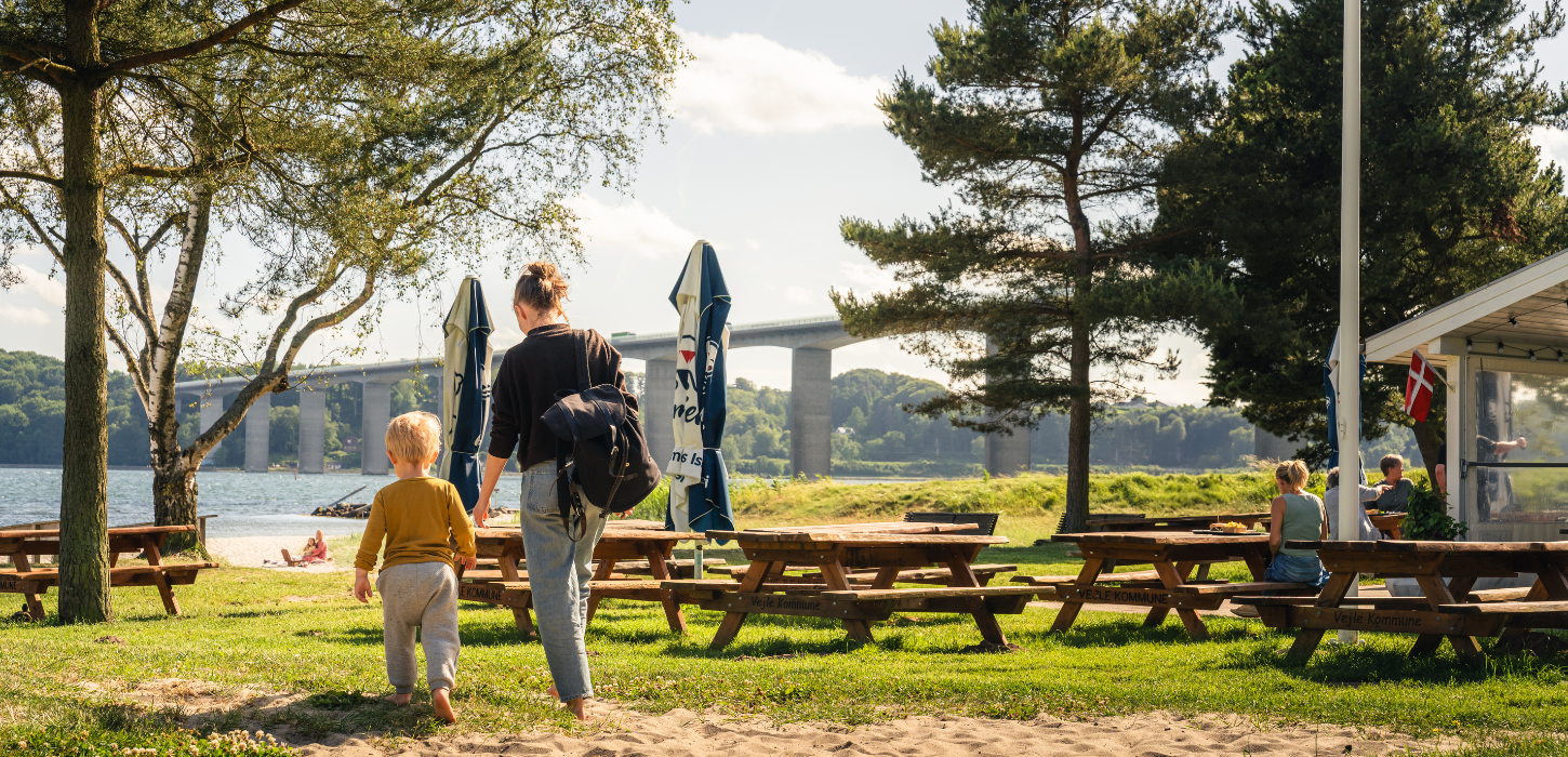 Familie går i sandet ved Albuen Strand ved Vejle Fjord